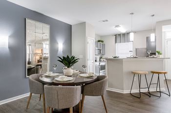 A dining area with a table and chairs and a kitchen in the background
